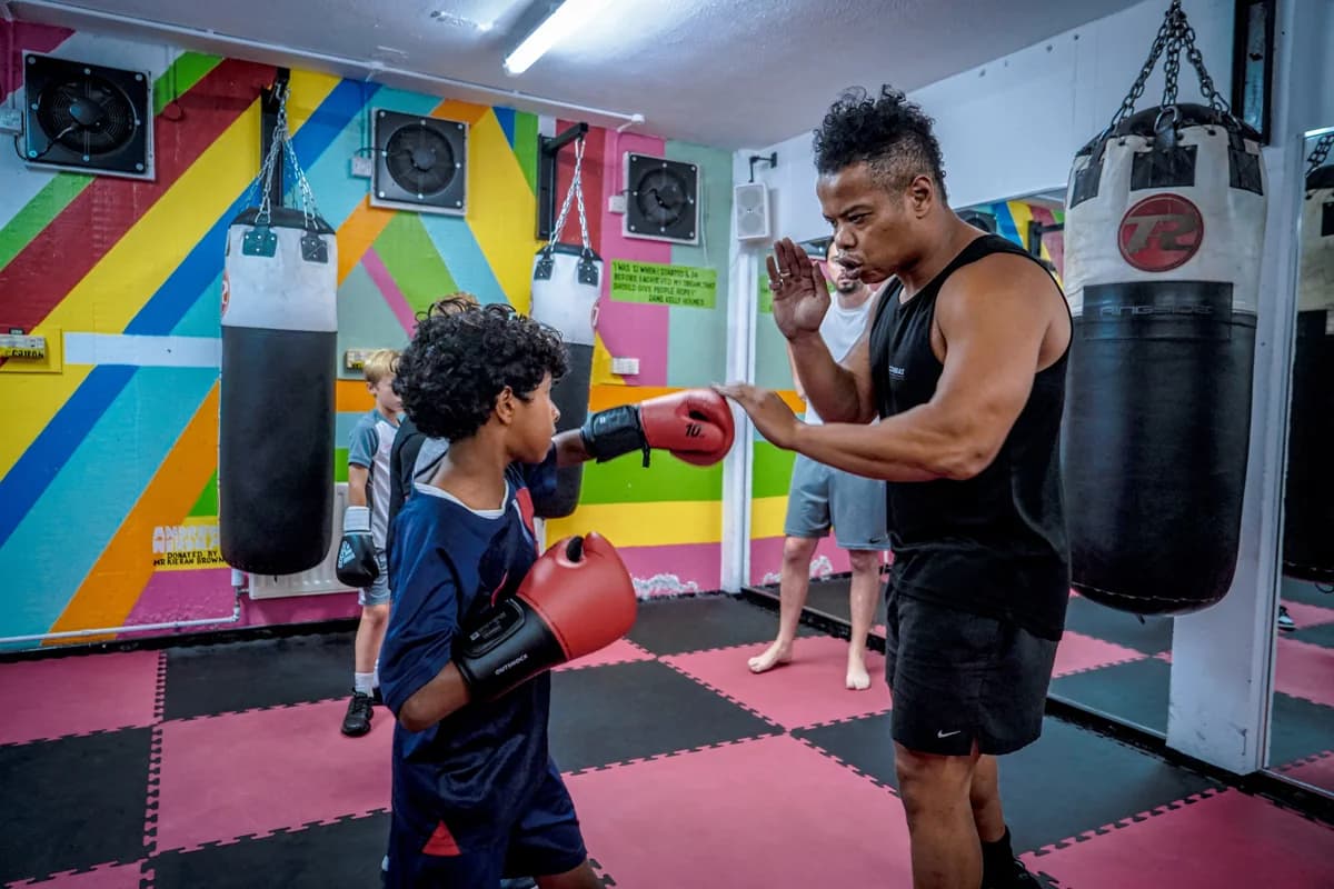 A young participant practising punches with a coach